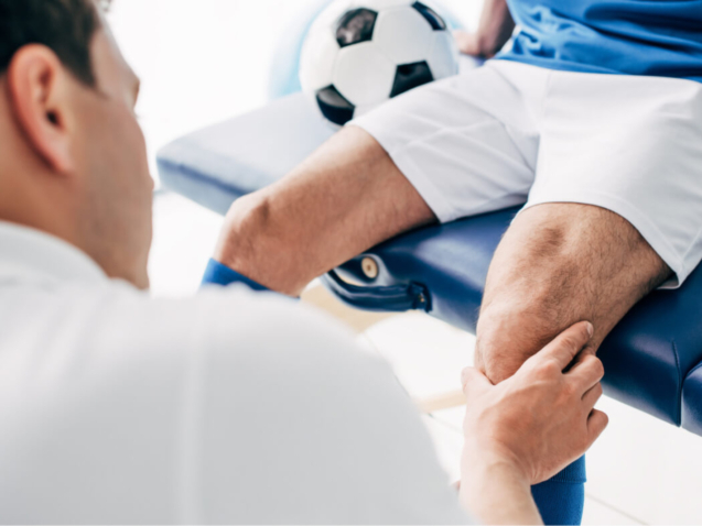 Physiotherapist-massaging-leg-of-football-player